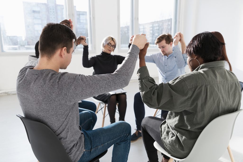 grupo de pessoas de várias etnias dando as mãos formando um círculo demonstrando um teste de competências comportamentais