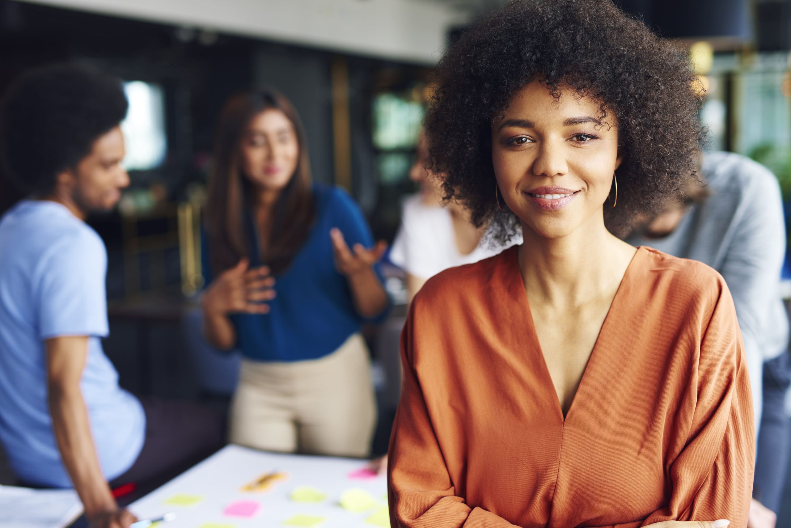 mulher negra, líder de equipe em primeiro plano. atrás está o seu time composto por três pessoas